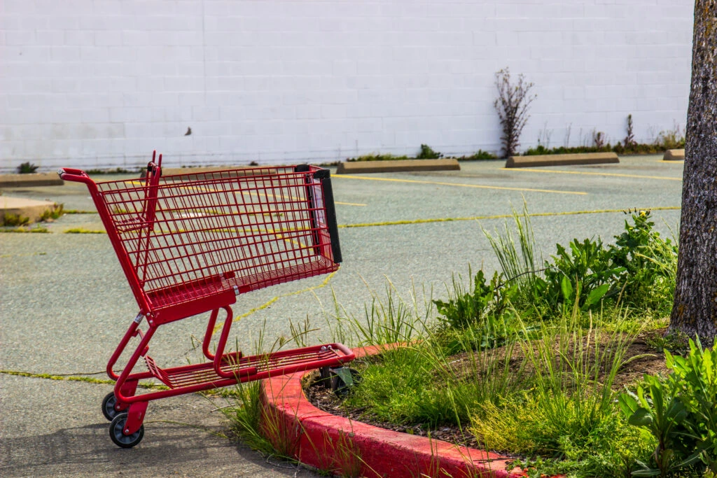 A red abandoned cart sits on a curb