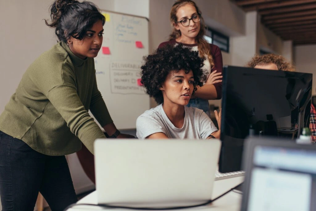 a group of young professionals looks at a computer screen